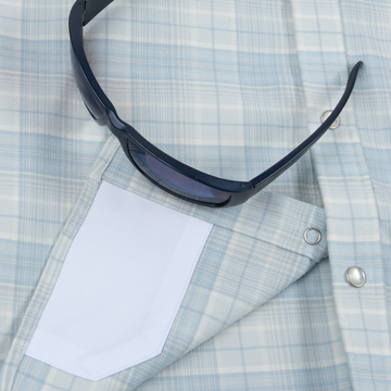 Blue checkered shirt with white pocket and dark sunglasses resting on it