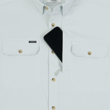 The Carolina Rig shirt with buttoned chest pockets and a phone partially tucked into the central pocket.