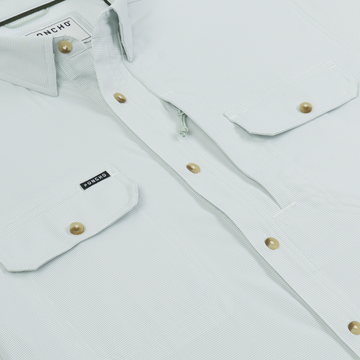 Close-up of a light-colored shirt with button pockets and a subtle pattern, featuring The Carolina Rig label.