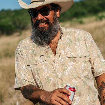 man leaning on fence wearing south texas camo shirt