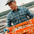 The Codfather plaid shirt worn by a man carrying a crate of oysters outdoors