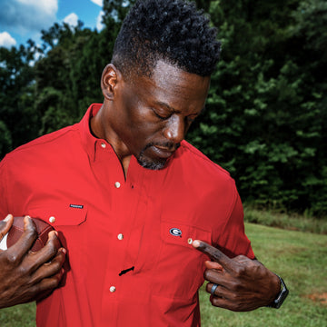 man holding football wearing red shirt pointing to Georgia logo on shirt