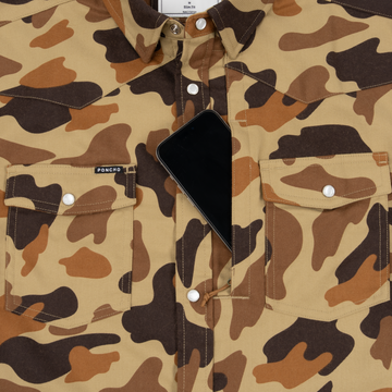 Close-up of The Delta Cowboy shirt in brown camouflage pattern with front snap-button pockets and a phone tucked inside one pocket