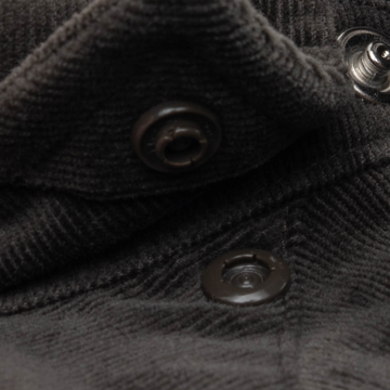 Close-up view of black textured fabric with snap buttons on The Dusty Burro shirt