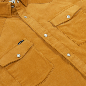 Close-up of mustard corduroy fabric with snap buttons and flap pockets on The Enfield shirt.