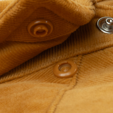 Close-up of button details and textured fabric in warm tones on The Enfield shirt