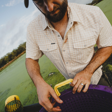 Man harvesting crawfish while wearing The Etouffee shirt