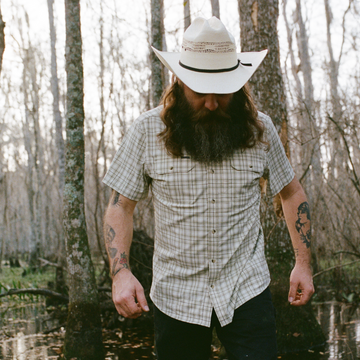 man wearing The Everglades shirt while walking through a swamp