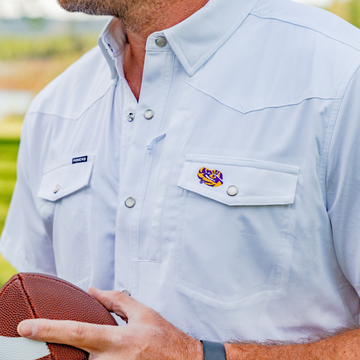 Man wearing a light shirt featuring The Eye of the Tiger logo holding a football outdoors