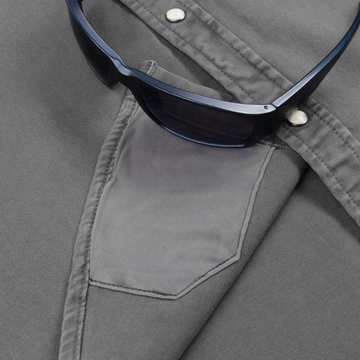 Close-up of a gray fabric pocket on The Falfurrias shirt with a pair of dark sunglasses resting on it.