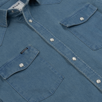 Close-up of The Fort Davis shirt in blue with snap buttons and two front flap pockets