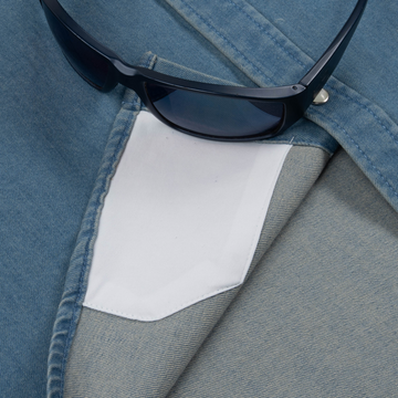 Close-up of The Fort Davis shirt pocket with black sunglasses resting on denim fabric showcasing shirt details.