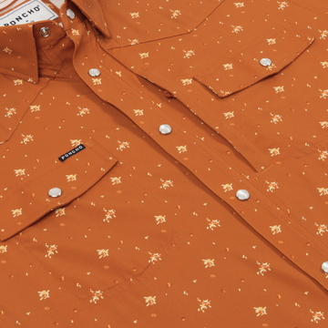 Close-up of The Fourth and Five shirt in rust color with a small floral pattern and snap buttons on pockets and front.