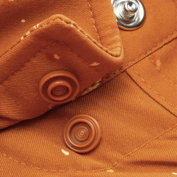 Close-up of orange fabric with button snaps and stitching detail from The Fourth and Five shirt.
