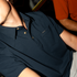 Close-up of a person wearing a navy shirt with a collar and buttons featuring a small "Poncho" logo, called The Front Porch.
