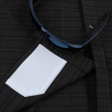 Close-up of a dark plaid shirt pocket with a white handkerchief and black sunglasses, highlighting The Gloucester shirt details.