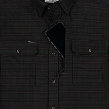 Close-up of The Gloucester shirt in dark plaid fabric with buttoned chest pockets, one holding a smartphone.