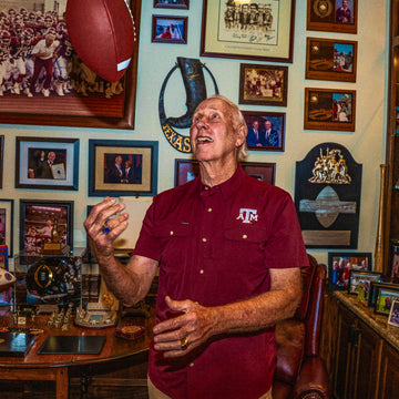 Man wearing maroon A&M shirt tossing football