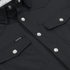 Close-up of black button-up shirt with snap buttons and flap pockets featuring The Newt label