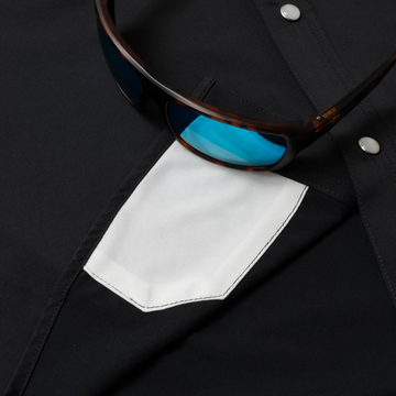 Close-up of The Jake shirt pocket with sunglasses resting on black fabric