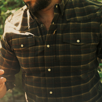 The John Colter black red and tan plaid men's outdoor shirt with button front and chest pockets outdoors