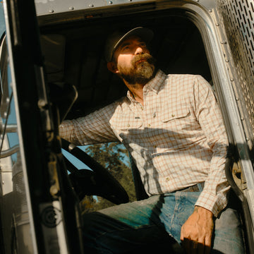 The Long Nose Pete mens outdoor shirt in maroon aqua white plaid with long sleeves inside a truck cab