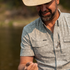 Man wearing The Lupine outdoor shirt with short sleeves and subtle pattern near water