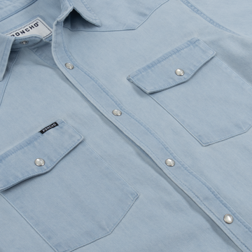 Close-up of light blue The Marfa shirt showing snap button details and two chest pockets with flaps.