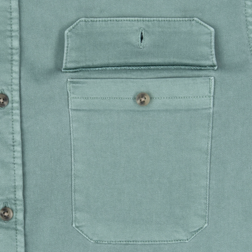 Close-up of a muted green buttoned chest pocket detail on The Mentone shirt.