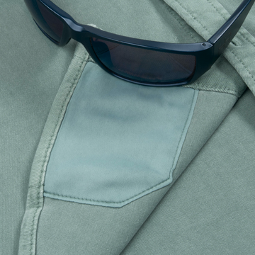 Close-up of a green shirt pocket detail on The Mentone shirt with black sunglasses resting on it