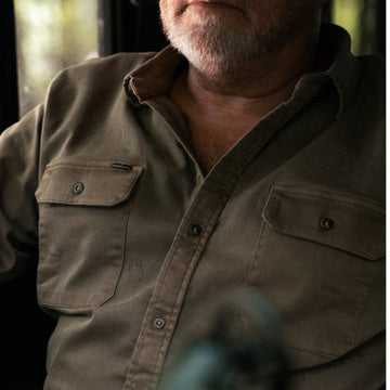 The Monteagle olive button up shirt with chest pockets worn by a bearded man outdoors
