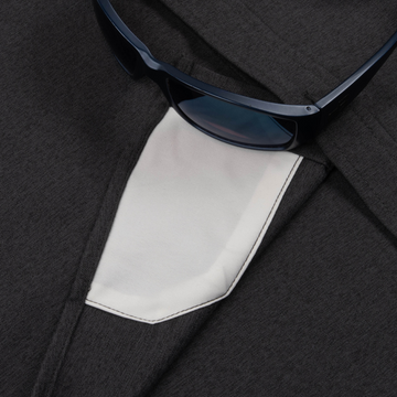 Close-up of dark fabric and a white pocket detail on The Nighthawk shirt with dark sunglasses resting on top.