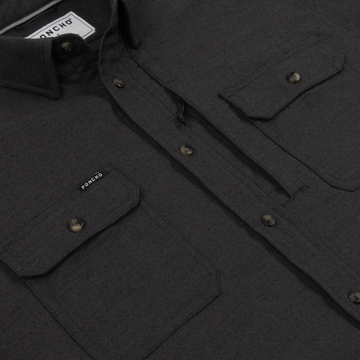 Close-up of The Nighthawk shirt in dark fabric with buttoned chest pockets and collar detail.