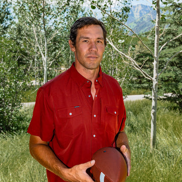 man holding football wearing red short sleeve shirt