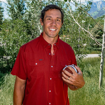 man holding football wearing red short sleeve shirt