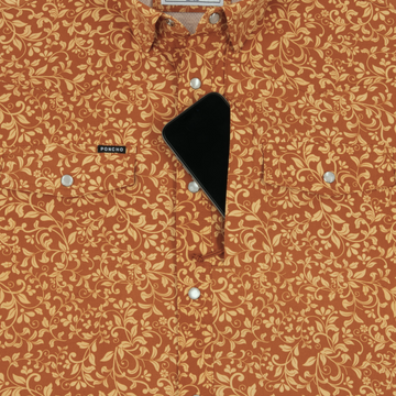 Close-up of The Occupy Left Field shirt in rust with a yellow floral pattern and a phone partially tucked into the chest pocket.