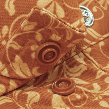 Close-up of an orange patterned fabric with snap buttons on The Occupy Left Field shirt.