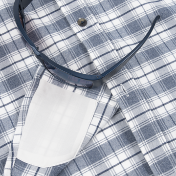 Close-up of The Pagosa shirt’s plaid fabric with a sunglass resting on the pocket, showcasing detail and texture.