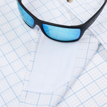 The Panga shirt with blue plaid pattern and blue tinted sunglasses resting on top