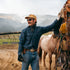 The Powder River men's western outdoor shirt in navy worn beside a saddled horse in mountain country