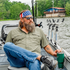 The Roaring Fork olive men's outdoor fishing shirt with button front and chest pockets on a boat