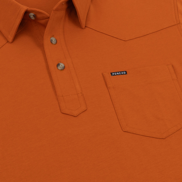 Close-up of an orange button-up shirt with a chest pocket featuring the Poncho label, part of The Speedway collection.