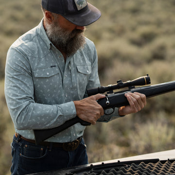 Man wearing The St. Helens shirt outdoors holding a rifle with scope