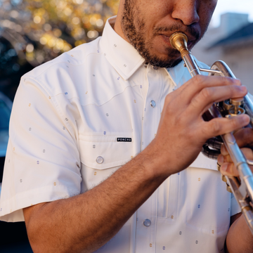 man playing the trumpet wearing the tchoupitoulas shirt