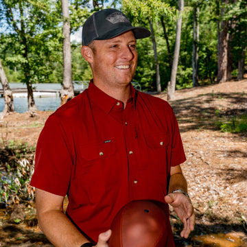 man holding football wearing red short sleeve shirt