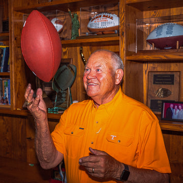 man wearing orange Tennessee shirt tossing football