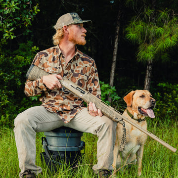 Man with dog holding shotgun