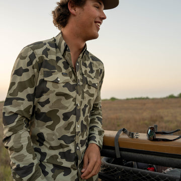 Man leans on railing while wearing The Zenaida shirt