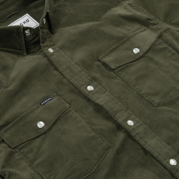 Close-up of olive green fabric shirt with snap buttons and two chest pockets featuring flap closures, labeled The Zilker.