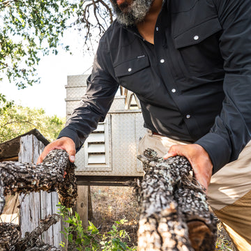 man holding wood wearing black long sleeve tuff-thread shirt